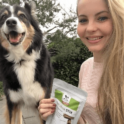 Hundefreundin mit ihrem glücklichen Hund und DOGS-HEART Spirulina Stix – gesunde Belohnung mit Liebe gefüttert.