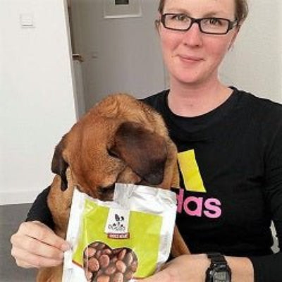 Mischling Hund glücklich mit Besitzerin und DOGS-HEART Lamm Hundefutter Verpackung